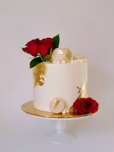 a white and gold cake with red roses on top