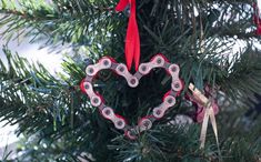 an ornament in the shape of a heart hangs on a christmas tree branch