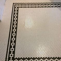 a black and white tiled floor in a bathroom with hexagonal tiles on the floor