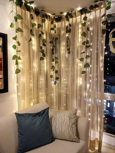 a living room filled with white couches covered in curtains and plants hanging from the ceiling