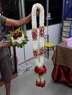 a man is holding up some flowers in front of a table with other decorations on it