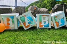 the letters baby spelled out with balloons in front of some rocks and trees near a suspension bridge