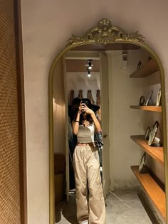 a woman taking a selfie in front of a mirror with shoes on the shelves