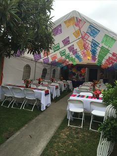 tables and chairs are set up under a tent for an outdoor event with colorful decorations