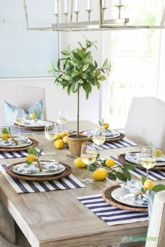 the table is set with plates, glasses and lemons on it for a meal