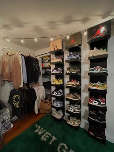 a room filled with lots of shoes and hanging clothes on the wall next to a green rug