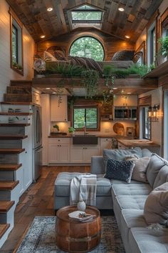 a living room filled with furniture next to a kitchen and stairs in front of a window