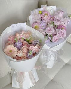 two bouquets of flowers sitting on top of a white table next to each other