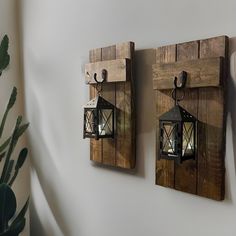 two wooden wall sconces mounted to the side of a white wall next to a potted plant