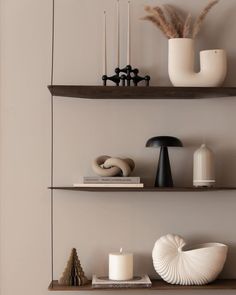 two shelves with candles, vases and other items on them