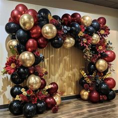 the balloon arch is decorated with black, red and gold balloons for a holiday celebration