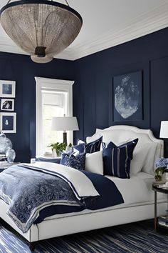 a blue and white bedroom with pictures on the wall above the bed, along with a chandelier