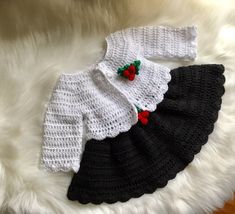 two black and white crocheted sweaters with red berries on the collarline