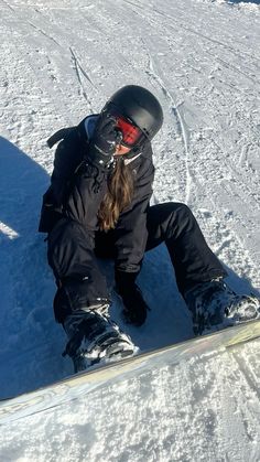 a snowboarder is sitting in the snow on his board