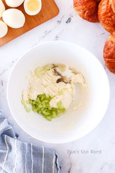 a bowl filled with cream cheese next to croissants