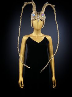 a mannequin with gold braids and jewels on it's head wearing a black dress