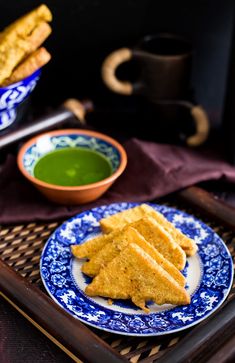 some food is on a blue and white plate next to a cup of green tea