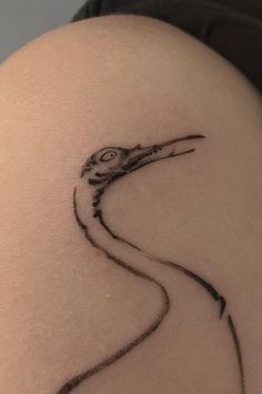 a bird tattoo on the back of a woman's thigh, with black ink