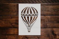 a hot air balloon cut out on top of a wooden wall next to a piece of paper