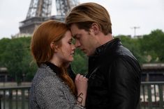 a man and woman standing next to each other in front of the eiffel tower