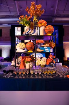 a table topped with lots of glasses filled with flowers and basketballs on top of it