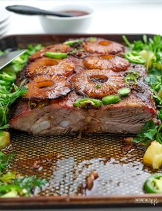 a piece of meat with pineapples on top and green vegetables in the background