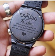 a person holding a watch in their hand with spanish words on the dial and heart