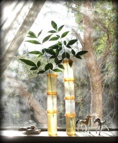 two tall yellow vases sitting on top of a window sill next to a tree