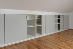 an empty room with white cabinets and hard wood floors