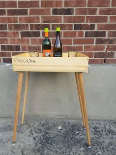 two bottles of wine sitting on top of a wooden table next to a brick wall