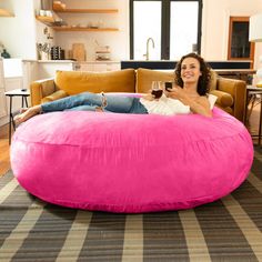 a woman sitting on a pink bean bag chair holding a wine glass in her hand