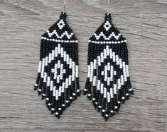 pair of black and white beaded earrings on wooden background with copy space for text