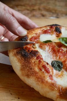 a person cutting into a pizza with a knife