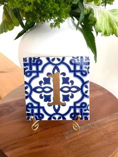 a blue and white tile with a gold handle on a wooden table next to a potted plant