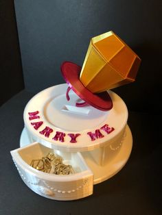 a cake with a hat on top that says happy birthday and gold rings around it