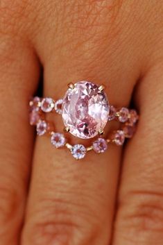 a woman's hand with a pink diamond ring on her left and an engagement band