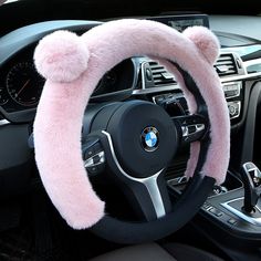 a car steering wheel cover with pink fur on the top and bottom, sitting in front of a dashboard