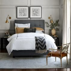 a bed with white sheets and pillows in a bedroom next to two framed pictures on the wall