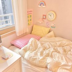 an unmade bed sitting next to a window in a room with white curtains and pink walls