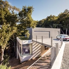 the house is surrounded by trees and fenced in area with cars parked on it