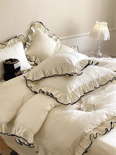 a bed with white sheets and black ruffles