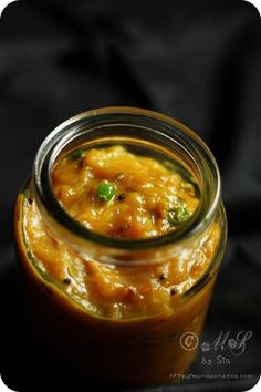 a glass jar filled with food sitting on top of a black cloth covered tablecloth