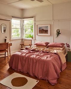 a bed sitting in a bedroom next to a wooden table and chair on top of a hard wood floor