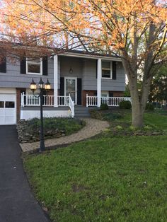 a gray house with white trim and black shutters on the front door is shown