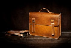 a brown leather briefcase sitting on top of a wooden floor