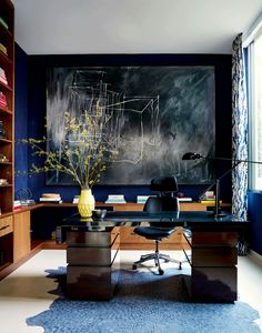 an office with blue walls and wooden flooring is pictured in this image, it has a large painting on the wall