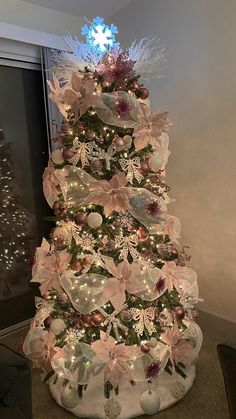 a christmas tree decorated with pink flowers and lights