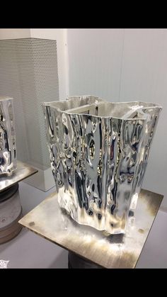 two silver vases sitting on top of a table