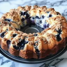 a bundt cake with blueberries and crumbled toppings on a black plate