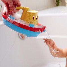 a baby is playing with a toy boat in the bathtub